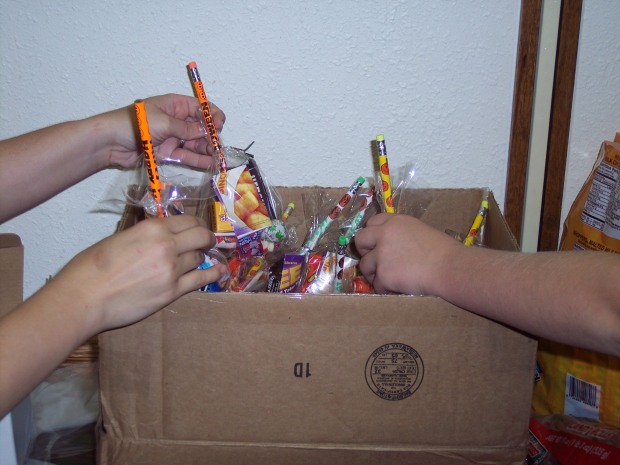 TEEN VOLUNTEERS drop bags of candy and treats into a box, as preparations were made last Friday for trick-or-treating at the library. Children are invited to attend a Halloween Carnival from 4-5:30 p.m. in the Whiteacre Room. Activities will include face painting, a game and a Halloween craft.